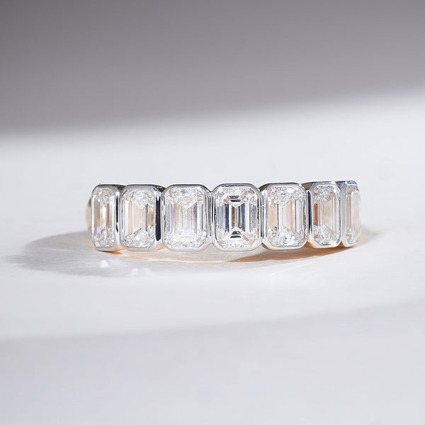 Front view of a 1.8 Ct emerald-cut half eternity band in yellow gold with a sleek prong setting.