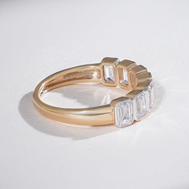 Angled view showing the side profile of the emerald-cut half eternity band in yellow gold.