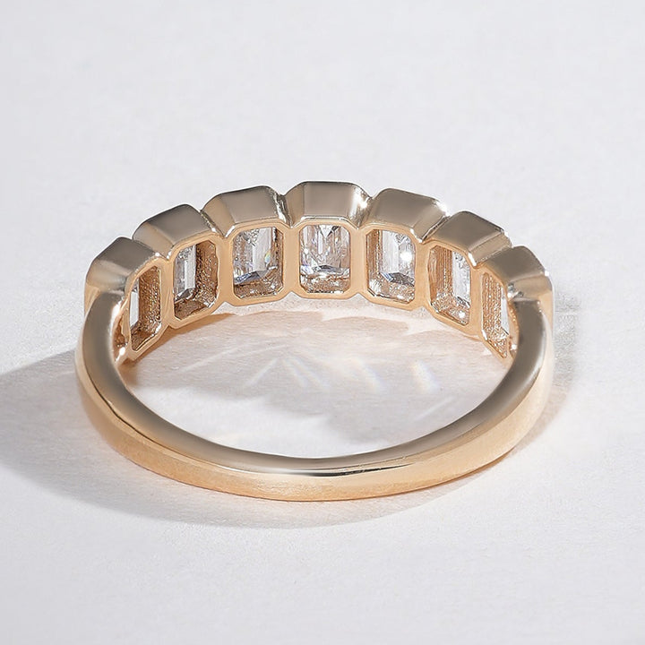Top-down view of the half eternity band displaying emerald-cut diamonds set in yellow gold.