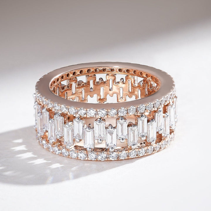 Angled view of rose gold eternity band with alternating baguette and round diamonds in a full-circle design.