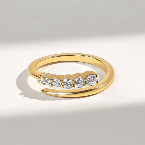 Gold open ring with diamonds descending in size on a light gray background