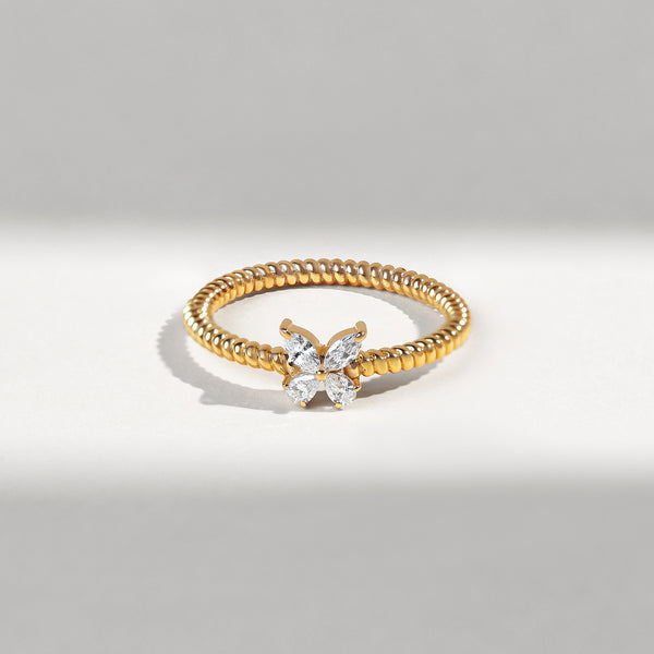 Gold ring with diamond butterfly design on a gray background
