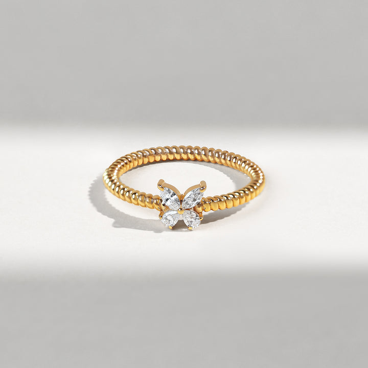 Gold ring with diamond butterfly design on a gray background