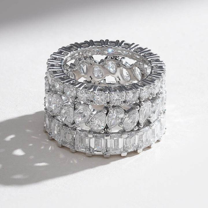 Top-down angle highlighting continuous triple rows—pavé top, pear-round center, baguette bottom—on polished white-gold eternity band.