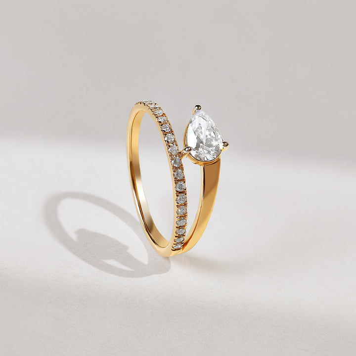 Gold ring with a pear-shaped diamond on a light gray background