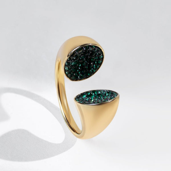 Gold ring with green gemstones on a white background