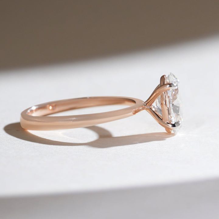 Side profile of rose gold oval-cut diamond solitaire ring with a slender, polished band.