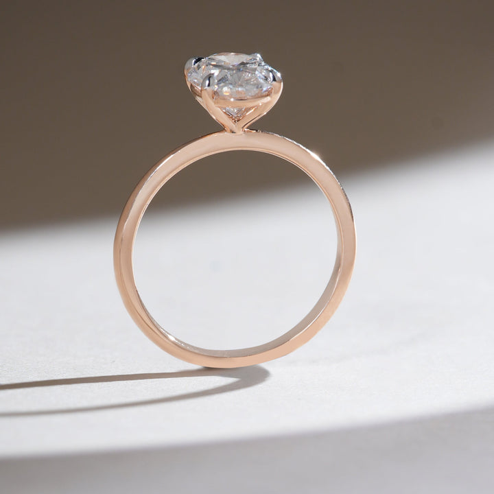 Slim rose gold band holding a 2-carat oval-cut diamond solitaire in a minimalist setting.