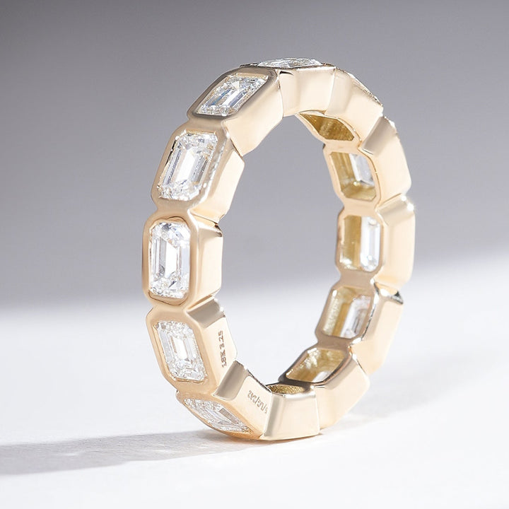 ide angled view of 3 Ct Bezel Emerald Eternity Band showcasing bezel-set diamonds.