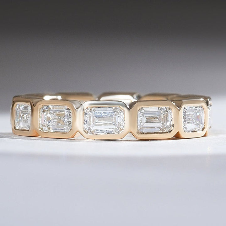 Front view of 3 Ct Bezel Emerald Eternity Band with bezel-set emerald-cut diamonds in gold.