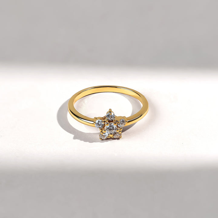 Gold ring with a flower-shaped diamond design on a light gray background