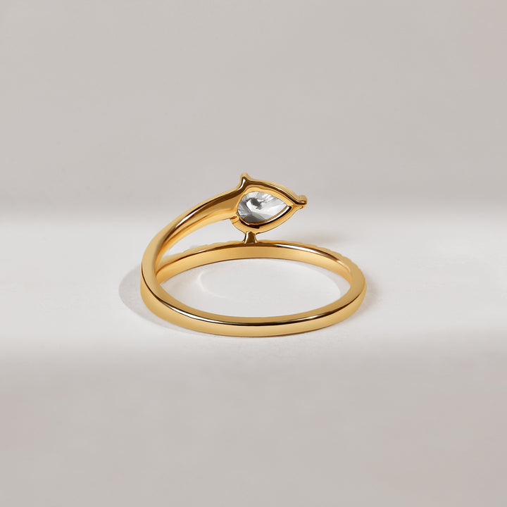 Gold ring with a pear-shaped diamond on a light gray background