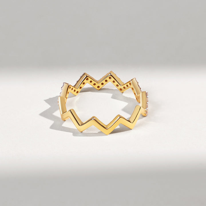 Gold ring with a zigzag design on a light gray background