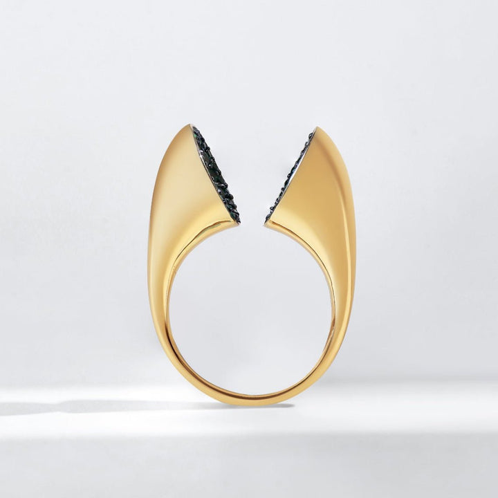 Gold ring with green gemstones on a light gray background vertical look