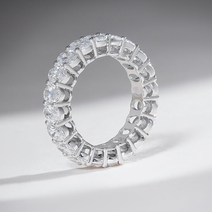 Standing profile of white gold 4-carat oval diamond eternity band with shared prong setting.