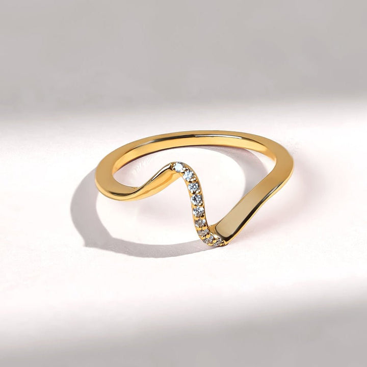 Gold ring with a subtle design on a light gray background