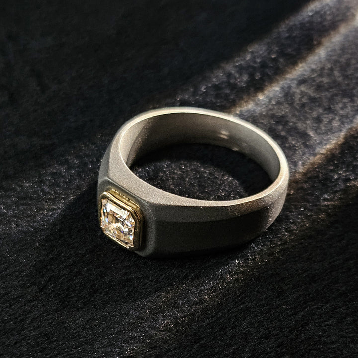 0.8 Ct Colossus Titanium Ring resting flat on surface with emerald-cut bezel diamond.