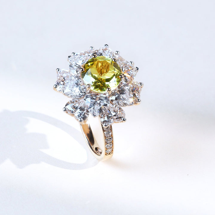 High jewelry statement ring featuring ornate floral diamond halo around a green gemstone.
