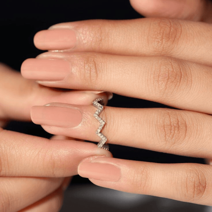 Close-up of a hand wearing a whit gold ring with a zigzag pattern