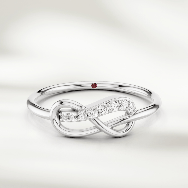 Infinity knot diamond ring in gold with slim polished band and red gemstone accent