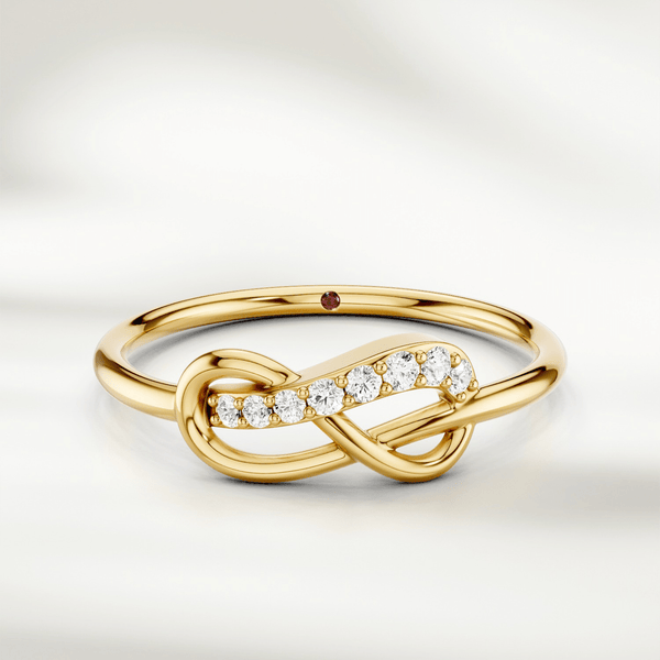 Infinity knot diamond ring in gold with slim polished band and red gemstone accent