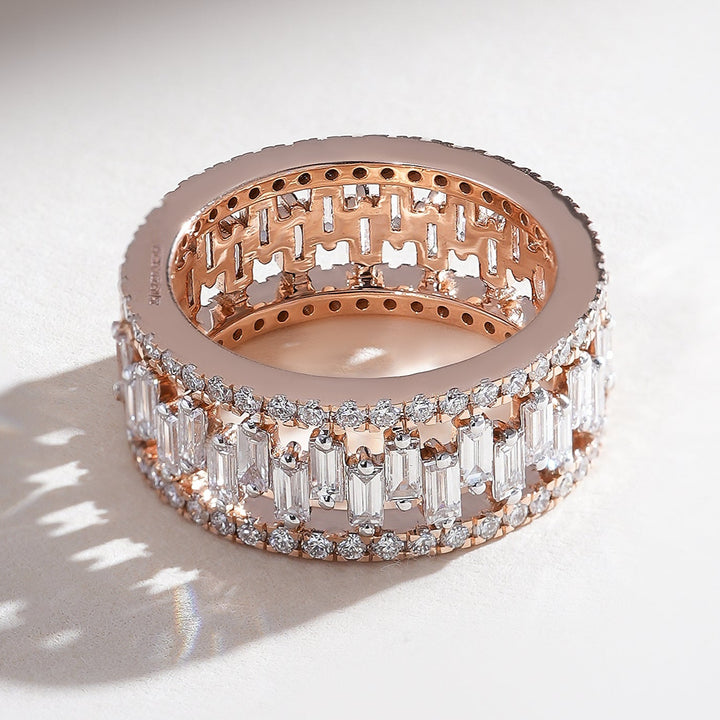 Angled view of rose gold eternity band with alternating baguette and round diamonds in a full-circle design.