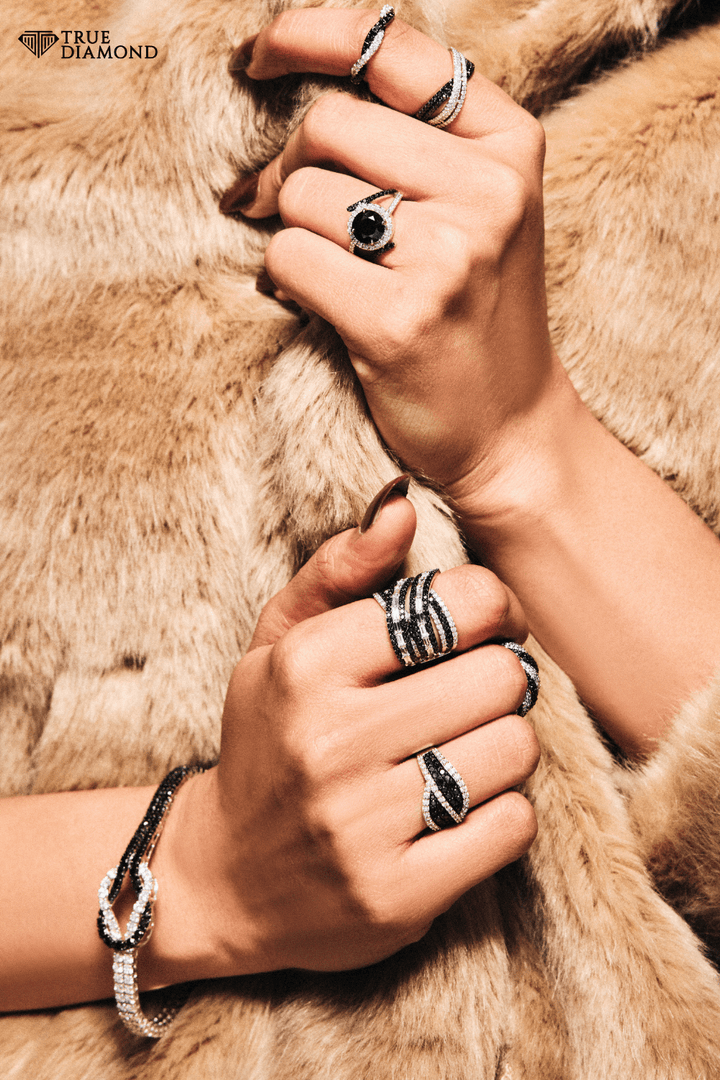 Close-up of hands wearing multiple rings on a fur surface with 'True Diamond' branding.