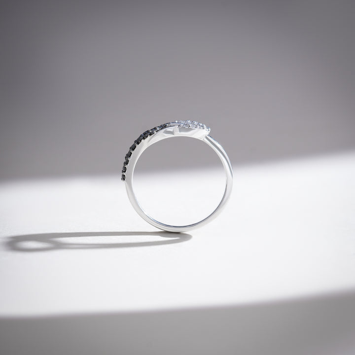 Top view of white gold ring with curved split shank and pavé-set black and white diamonds.