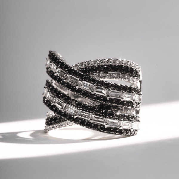 Wide criss-cross ring with alternating rows of black pavé diamonds and baguette-cut white diamonds in white gold.