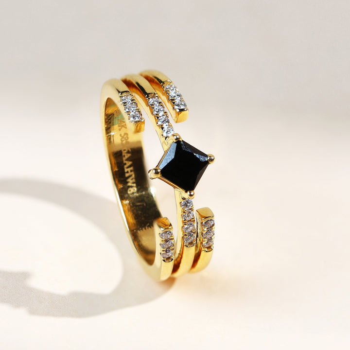 Luxury yellow gold ring featuring a black princess-cut diamond and twin rows of white accent diamonds – angled side view