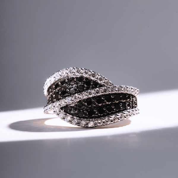White gold ring with interwoven rows of black pavé diamonds framed by white diamonds in a wave-like design.