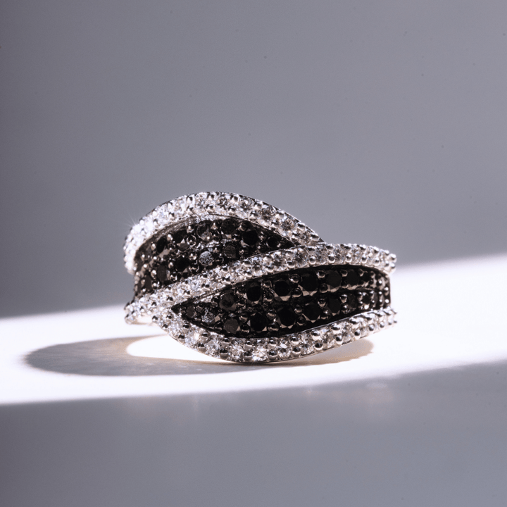 White gold ring with interwoven rows of black pavé diamonds framed by white diamonds in a wave-like design.