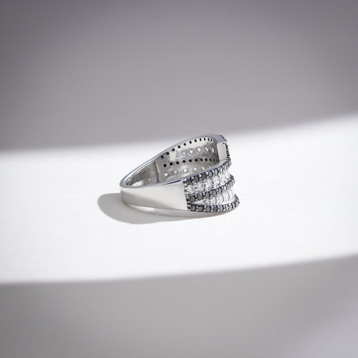 Side profile of spiral diamond ring in white gold, featuring black pavé framing brilliant white stones.