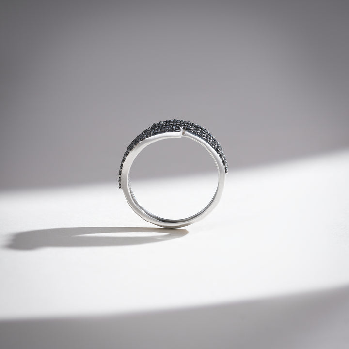 Slim profile view of spiral diamond ring with contrasting black pavé accents in white gold.