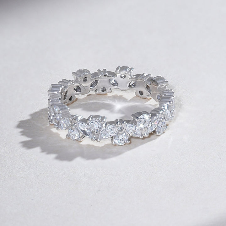 Angled view of white gold eternity band featuring alternating marquise and round diamonds in a full-circle setting.