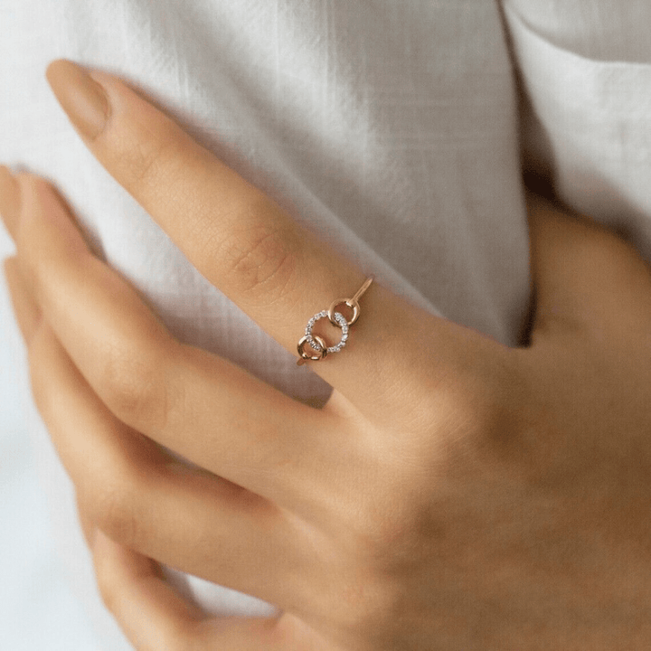 Woman wearing connected circles diamond ring on finger.