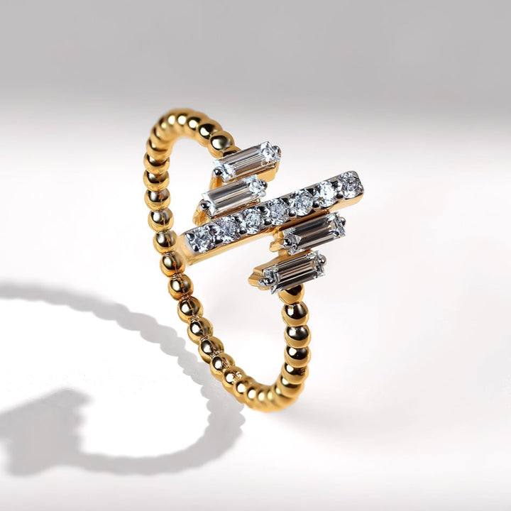 Angled side view of the beaded gold band with baguette and round diamonds