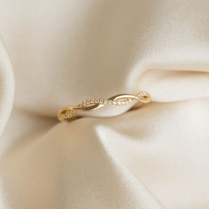 Gold ring with small diamonds on a beige fabric background