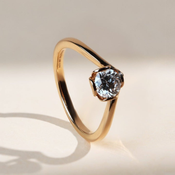 Angled view of solitaire ring showing the diamond held in a petal-inspired bezel.