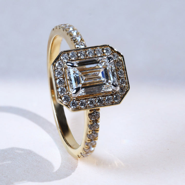Emerald-cut 1 ct diamond solitaire ring with halo setting in yellow gold