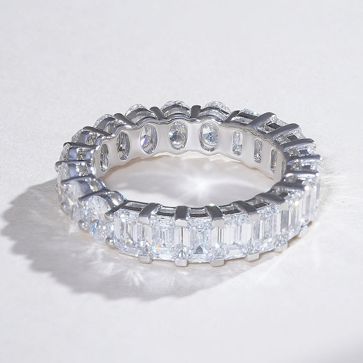 Angled view of white gold eternity ring showcasing alternating oval and emerald-cut diamonds for dynamic sparkle.