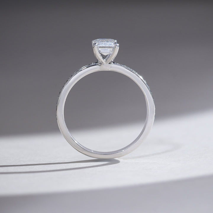 Profile shot displaying the solitaire’s prong setting and thin pavé diamond band.