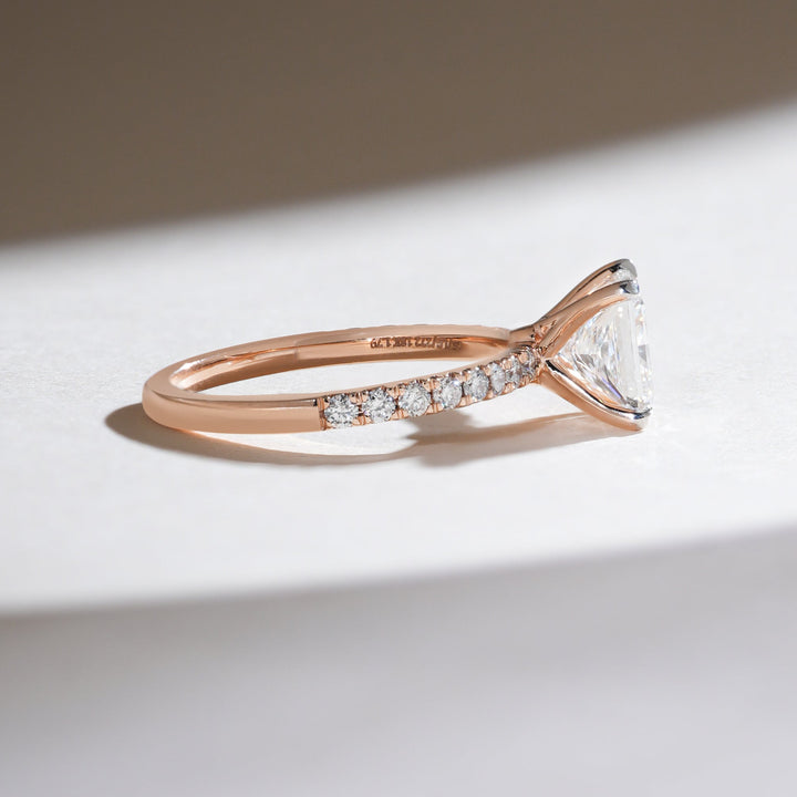 Side view showing the pavé diamond detailing on the rose gold band and the elegant prong setting of the princess-cut diamond.