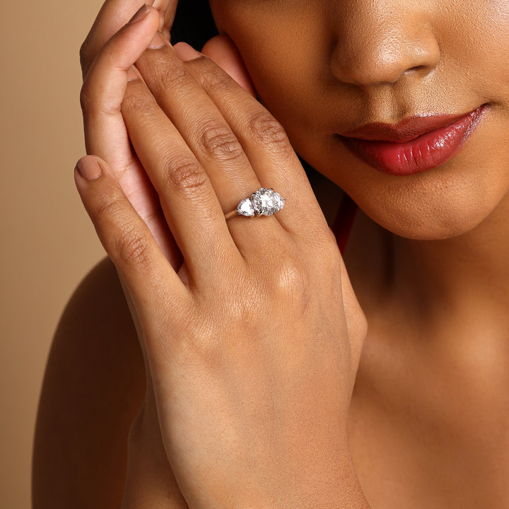 Woman wearing Evermore 3.5 Ct Three Stone Ring in 18K white gold, close-up of ring on hand, diamonds sparkling elegantly.