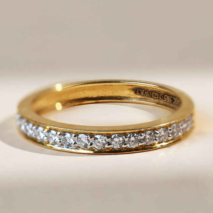 Side angle of flat eternity ring showing continuous row of diamonds on gold band.