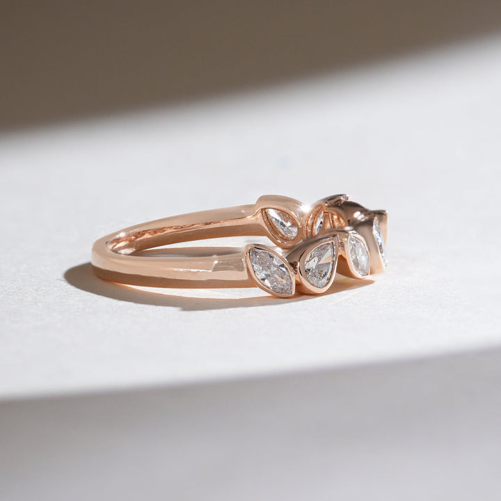 Side angle showcasing alternating marquise and pear-shaped diamonds in a rose gold half-eternity band.