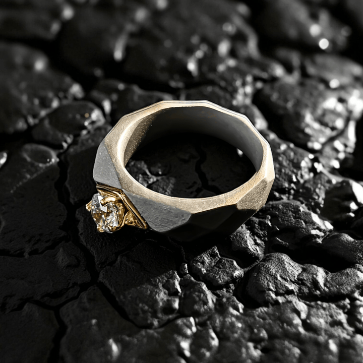 Close-up of 0.5 Ct Helios Titanium Ring on a rugged black stone surface, highlighting the diamond and faceted titanium body — detail shot.