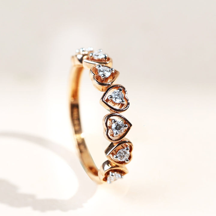 Side angle of rose gold ring with aligned heart settings
