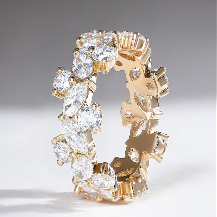 Standing view of 18K yellow gold eternity band showcasing alternating marquise and round diamonds set in a floral-like pattern.