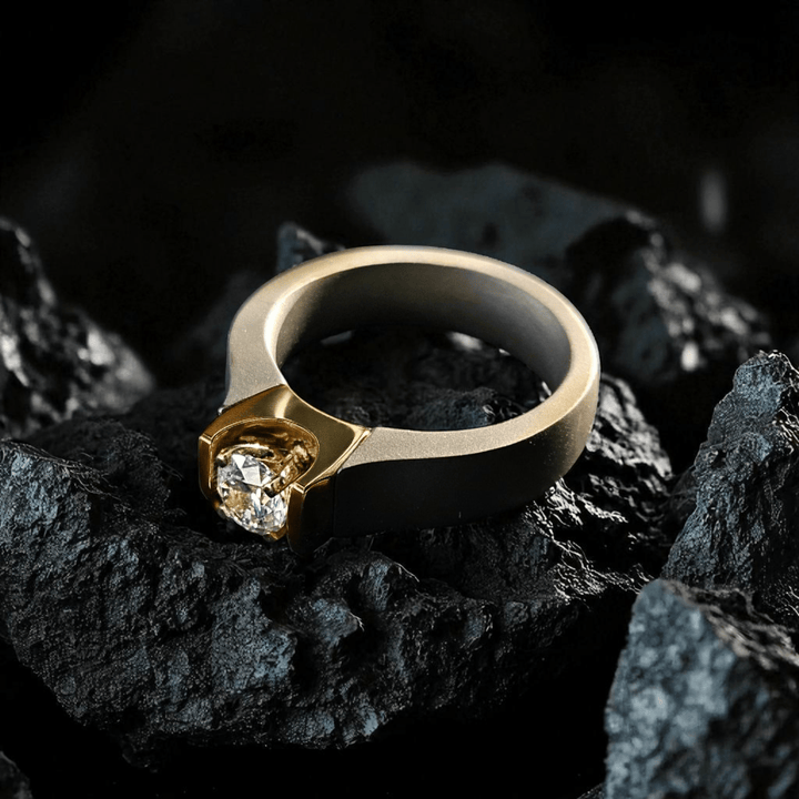 Obsidian Flame Titanium Ring placed on black rocks, showing rugged gold-titanium contrast.